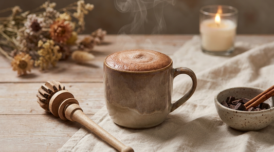 Tasse mit frisch zubereitetem zeremoniellem Kakao und Schneebesen auf Holztisch